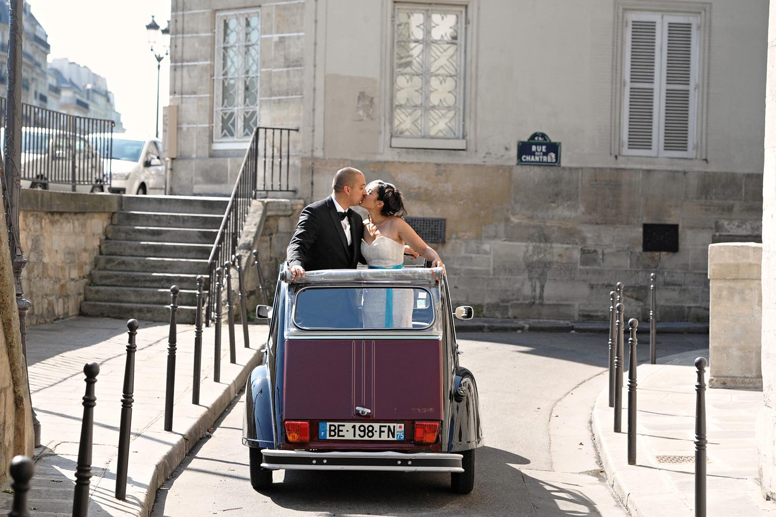Newlyweds kissing in a vintage car on a Paris street